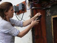 A graduate student installs a mini-grid device on a house in Bhutan