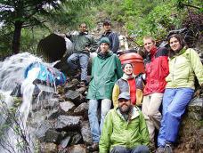 A group of students pose near the water pouring out of a culvert pipe