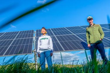 two students standing in front of a solar array