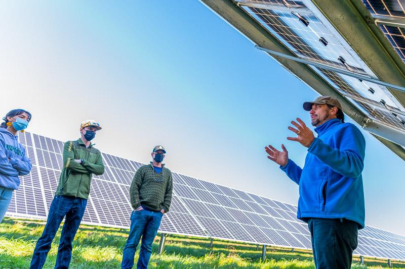 Three people standing in front of a solar array